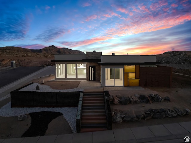 back house at dusk with a mountain view and a patio area
