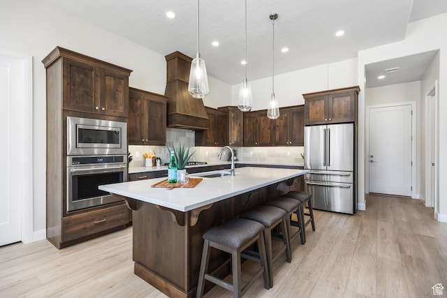 kitchen featuring sink, hanging light fixtures, dark brown cabinets, stainless steel appliances, and decorative backsplash