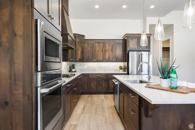 kitchen featuring sink, appliances with stainless steel finishes, tasteful backsplash, decorative light fixtures, and custom exhaust hood