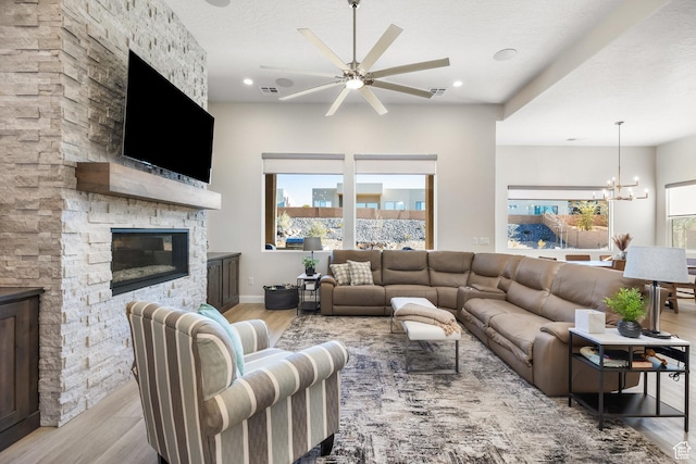 living room featuring light hardwood / wood-style flooring, a notable chandelier, a fireplace, and a textured ceiling