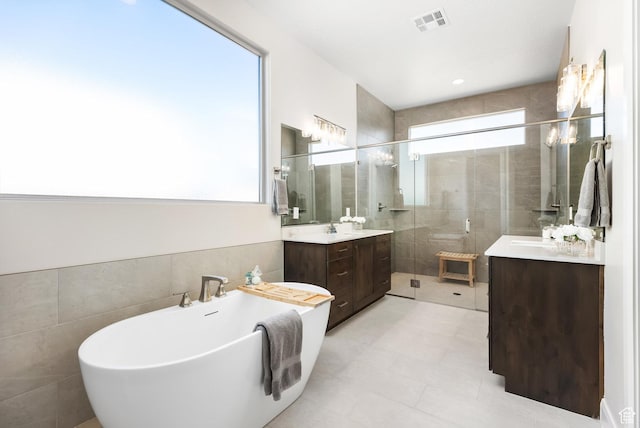 bathroom featuring vanity, a wealth of natural light, tile walls, and separate shower and tub