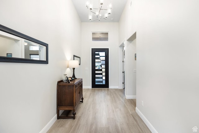 foyer with a notable chandelier, light hardwood / wood-style flooring, and a high ceiling