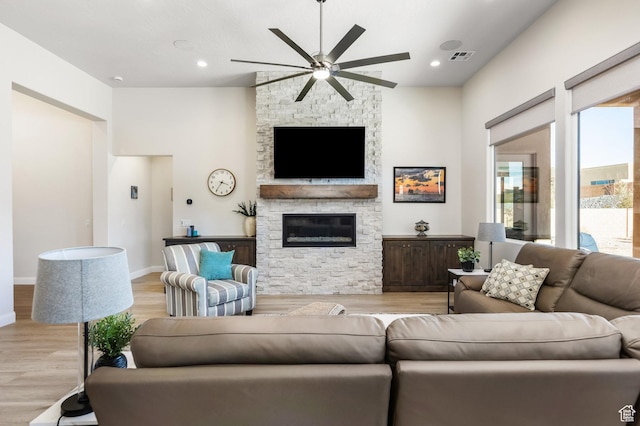 living room with ceiling fan, a fireplace, and light hardwood / wood-style flooring