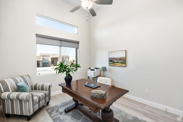 office featuring a high ceiling, ceiling fan, and light wood-type flooring