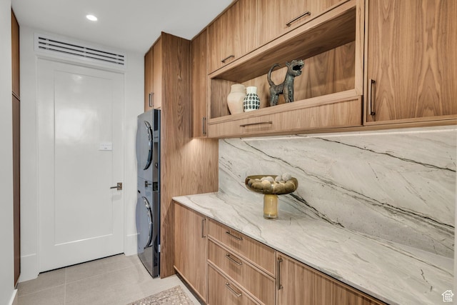 63 E Colima Rd, Washington, UT 84780 - kitchen with stacked washing machine and dryer, light stone countertops, light tile patterned flooring, brown cabinets, and open shelves