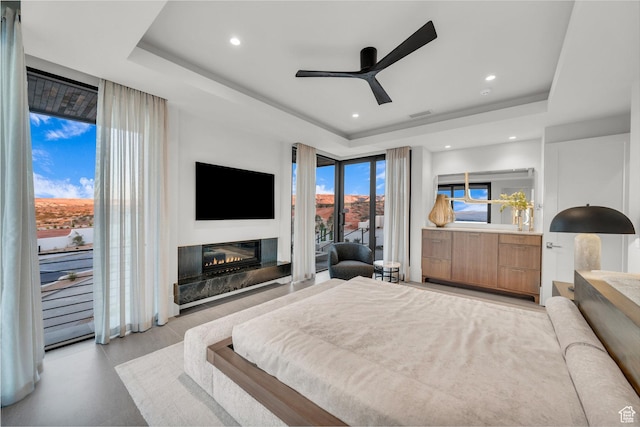 63 E Colima Rd, Washington, UT 84780 - bedroom featuring a tray ceiling, access to exterior, a glass covered fireplace, recessed lighting, and a ceiling fan