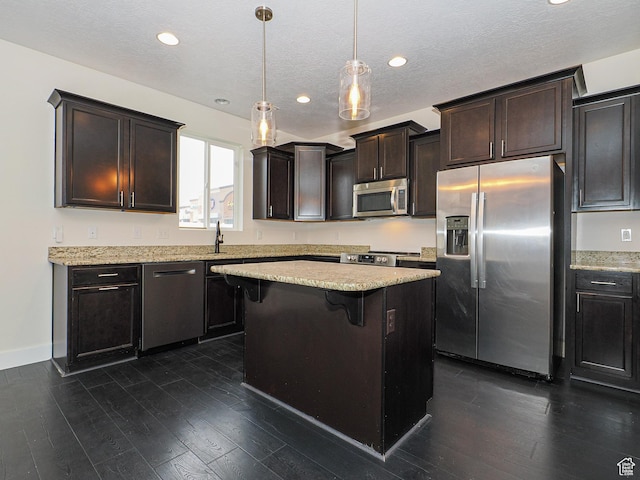 13364 S Stone Hayes Ct, Herriman, UT 84096 - kitchen featuring a kitchen island, decorative light fixtures, a kitchen bar, stainless steel appliances, and dark wood-type flooring