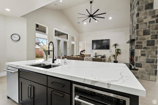 802 E Prairie Way, Washington, UT 84780 - kitchen featuring light stone counters, sink, a stone fireplace, and a center island with sink