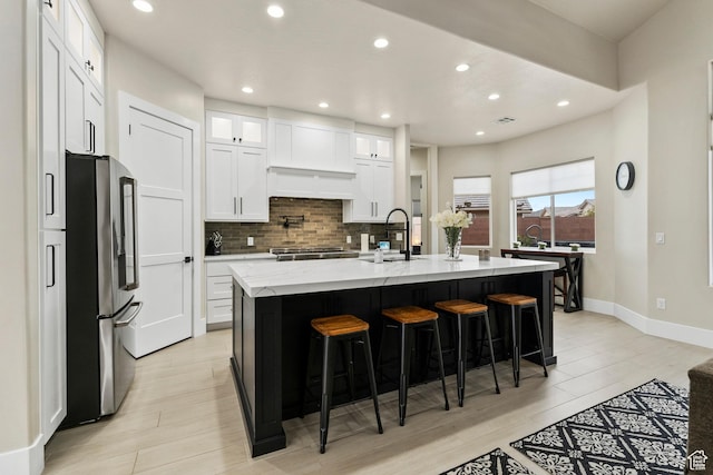 802 E Prairie Way, Washington, UT 84780 - kitchen with stainless steel refrigerator, an island with sink, sink, a breakfast bar area, and white cabinets