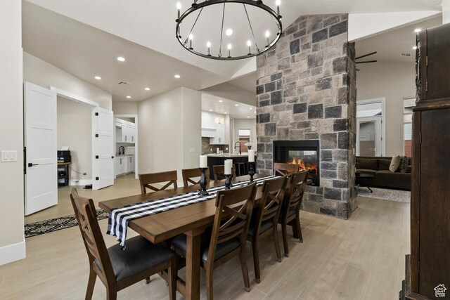802 E Prairie Way, Washington, UT 84780 - dining room with vaulted ceiling, a stone fireplace, an inviting chandelier, and light wood-type flooring