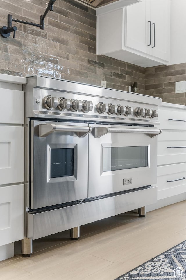 802 E Prairie Way, Washington, UT 84780 - kitchen featuring tasteful backsplash, light wood-type flooring, white cabinets, and range with two ovens
