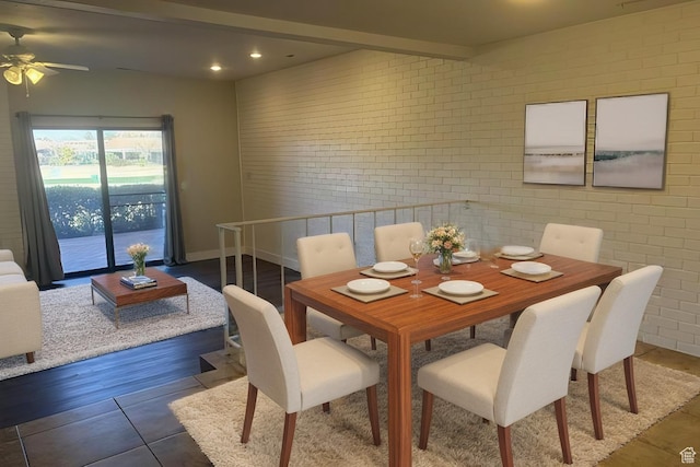dining area with dark hardwood / wood-style flooring and brick wall