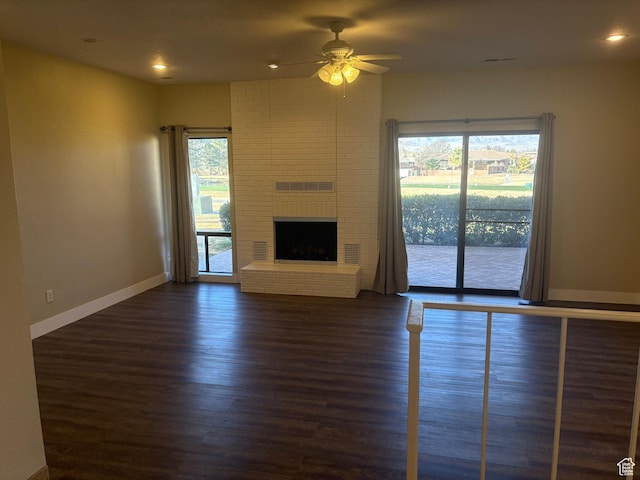 unfurnished living room featuring a fireplace, dark hardwood / wood-style floors, and ceiling fan