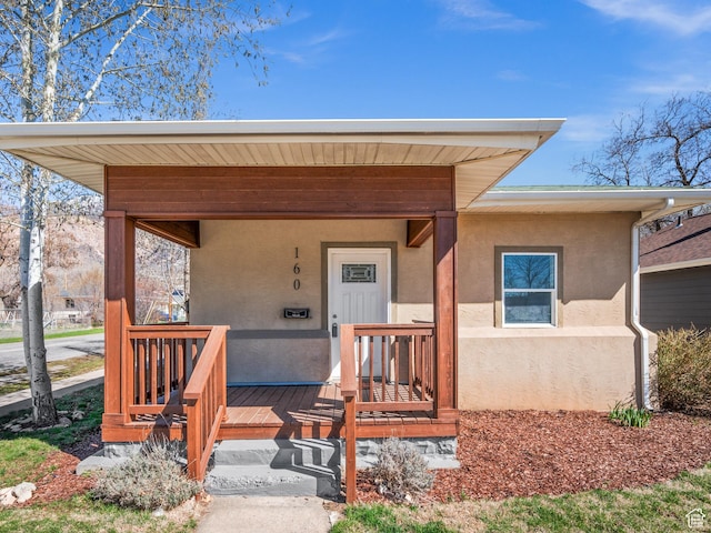 view of exterior entry with covered porch and stucco siding