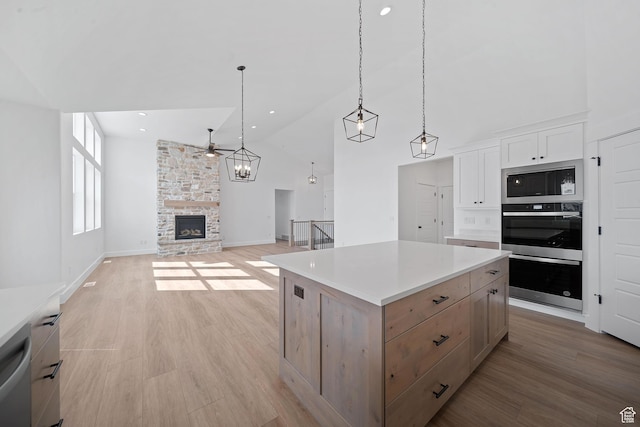 kitchen with pendant lighting, light hardwood / wood-style flooring, stainless steel appliances, white cabinets, and a kitchen island