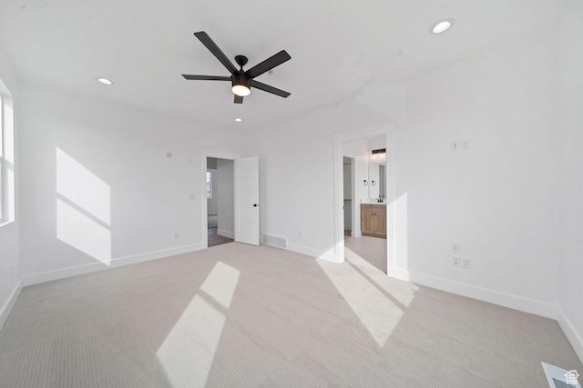 unfurnished bedroom featuring connected bathroom, light carpet, and ceiling fan