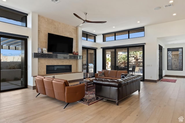 2015 S Pinnacle Cir, St George, UT 84790 - living room featuring ceiling fan, a large fireplace, light hardwood / wood-style floors, and a high ceiling