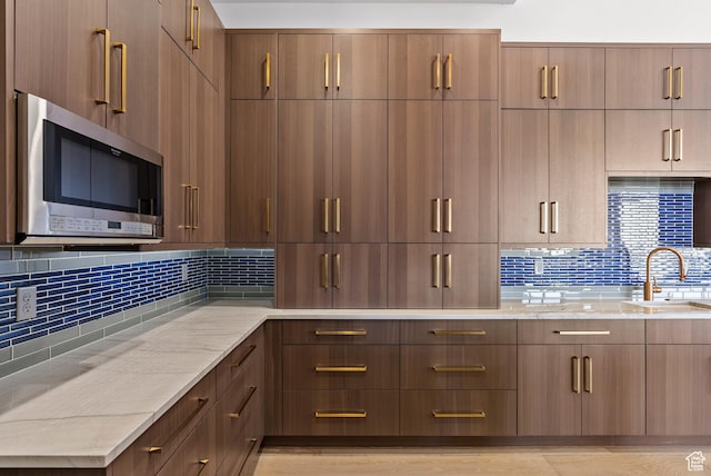2015 S Pinnacle Cir, St George, UT 84790 - kitchen featuring tasteful backsplash, light stone countertops, sink, and light hardwood / wood-style flooring