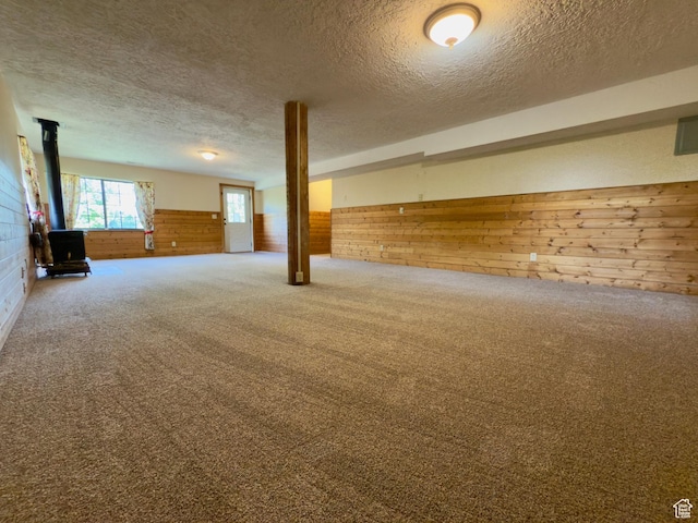 485 S Woodland Hills Dr, Woodland Hills, UT 84653 - below grade area featuring wooden walls, a wood stove, a textured ceiling, carpet, and wainscoting
