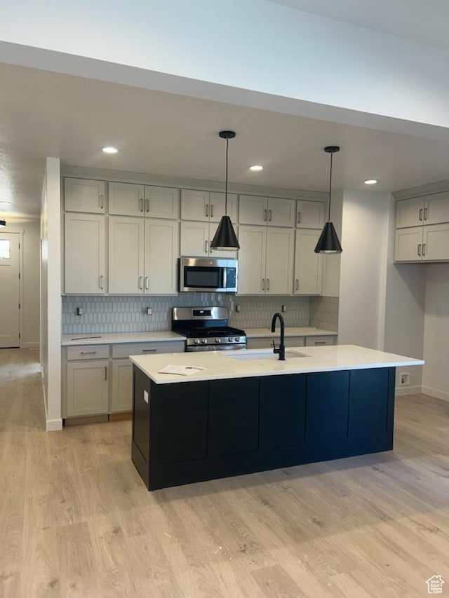 kitchen featuring stainless steel appliances, light wood finished floors, a sink, light countertops, and recessed lighting