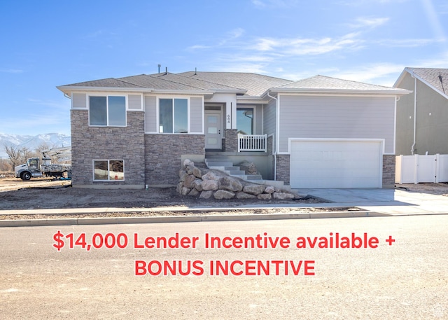 684 S 3550 W Unit 131, West Weber, UT 84401 - view of front of property featuring stone siding, concrete driveway, an attached garage, a mountain view, and roof with shingles