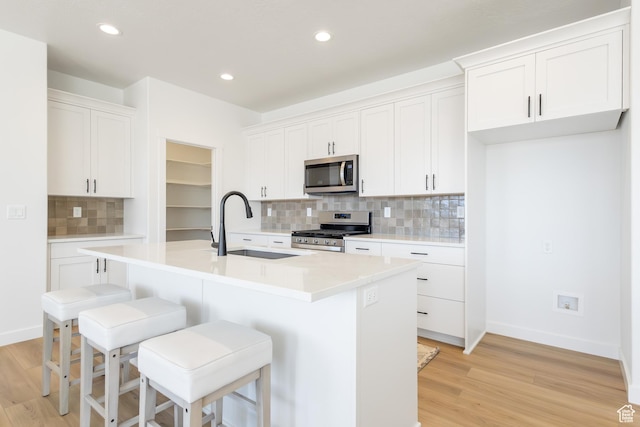 684 S 3550 W Unit 131, West Weber, UT 84401 - kitchen featuring stainless steel appliances, a sink, backsplash, a center island with sink, and light wood-style floors