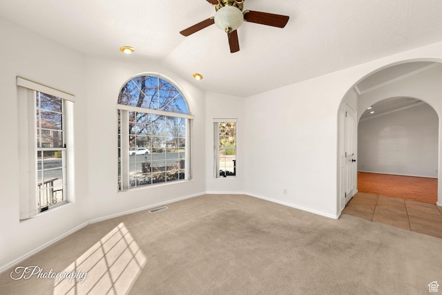 carpeted spare room featuring vaulted ceiling and ceiling fan