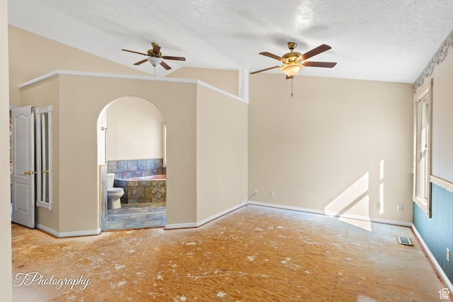 unfurnished room featuring ceiling fan, vaulted ceiling, and a textured ceiling