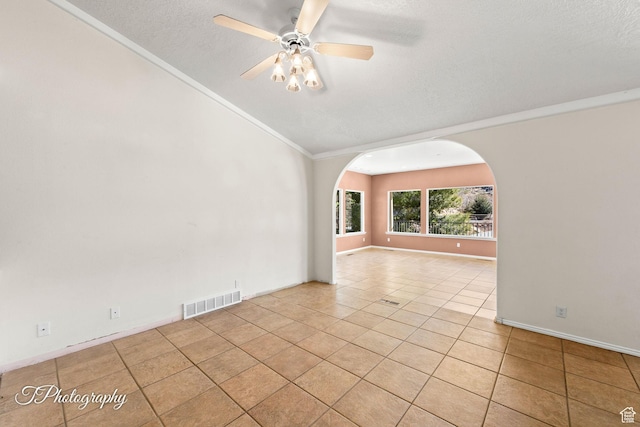 spare room with ornamental molding, light tile patterned floors, a textured ceiling, and ceiling fan