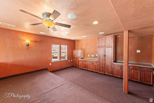 carpeted empty room with ceiling fan and a textured ceiling
