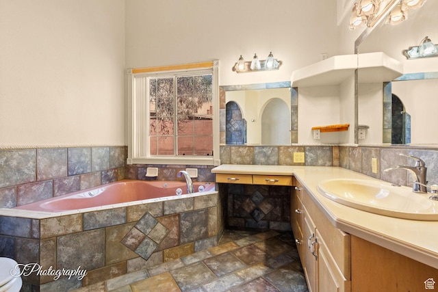 bathroom featuring tiled tub, vanity, and backsplash