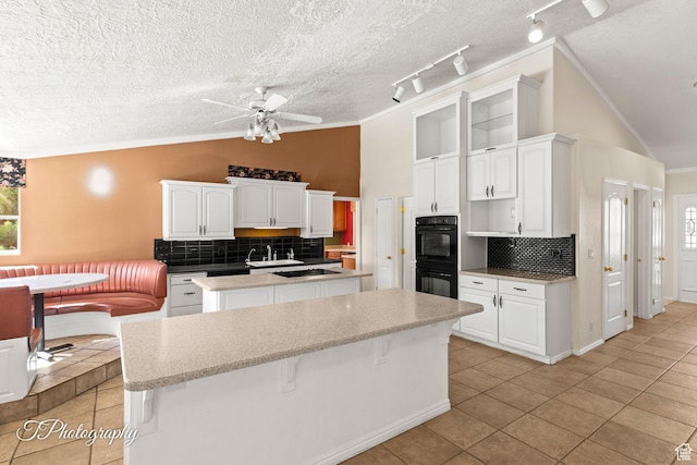 kitchen with white cabinetry, vaulted ceiling, black appliances, and a kitchen island