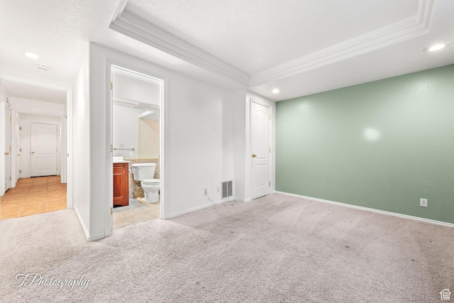 spare room with light carpet, a tray ceiling, and a textured ceiling