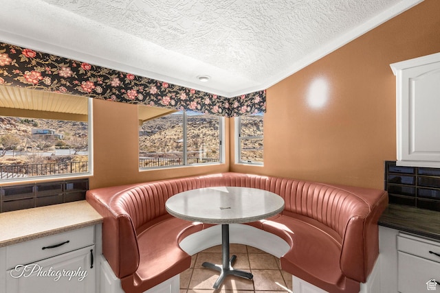 living area featuring breakfast area, crown molding, and a textured ceiling
