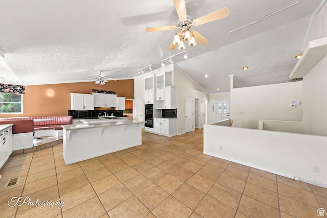 kitchen featuring white cabinetry, vaulted ceiling, a textured ceiling, and a kitchen island