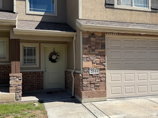 2044 N Evans Cove Loop W, Layton, UT 84041 - property entrance featuring a shingled roof, stucco siding, and stone siding