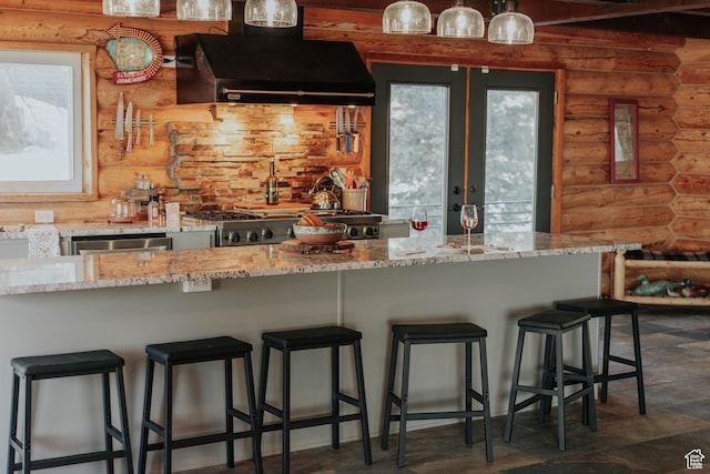 kitchen with light stone countertops, extractor fan, french doors, and rustic walls