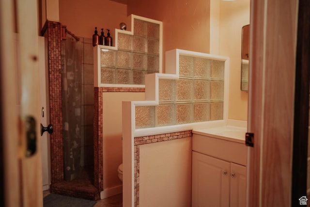 bathroom featuring toilet, walk in shower, and vanity