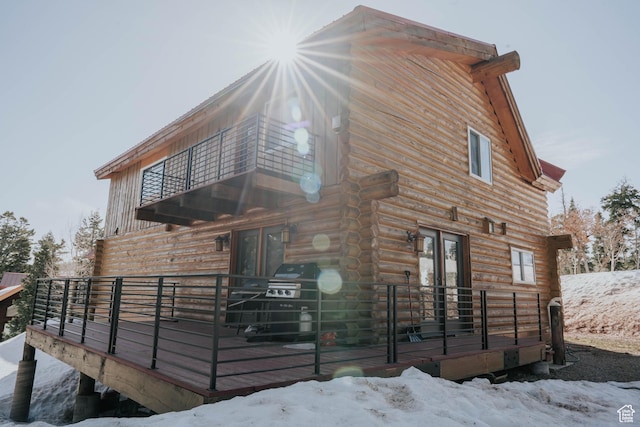 snow covered property featuring french doors, log exterior, and a balcony