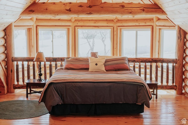 bedroom with multiple windows, light wood finished floors, and rustic walls