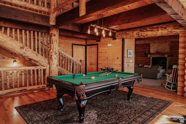 recreation room featuring log walls, a fireplace, beamed ceiling, wood finished floors, and pool table