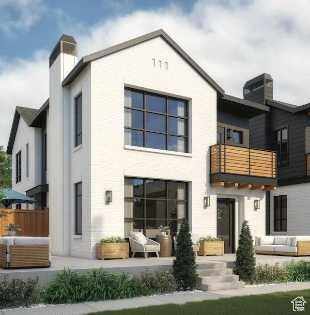 rear view of property with a balcony, an outdoor living space, and a patio area