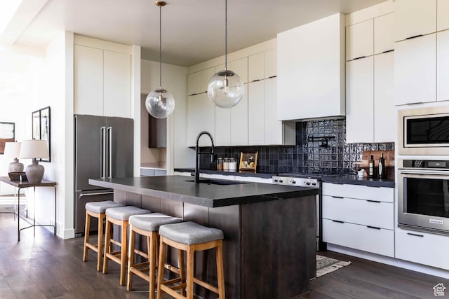 1318 Mahogany Way, Park City, UT 84098 - kitchen featuring pendant lighting, sink, stainless steel appliances, an island with sink, and decorative backsplash