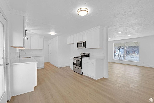 kitchen featuring a textured ceiling, light hardwood / wood-style flooring, white cabinets, and appliances with stainless steel finishes