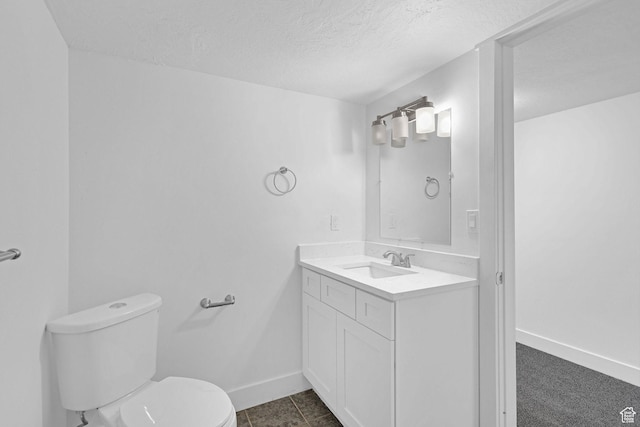 bathroom with tile patterned flooring, vanity, a textured ceiling, and toilet