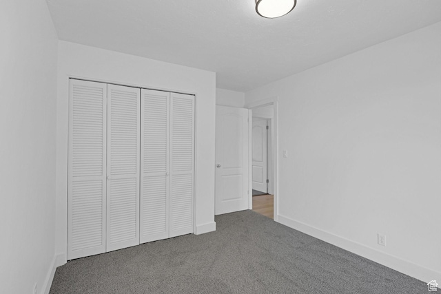 unfurnished bedroom featuring dark carpet and a closet
