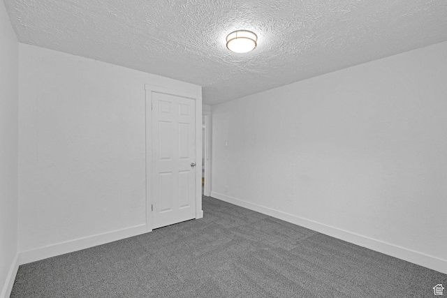 unfurnished room featuring a textured ceiling and dark carpet