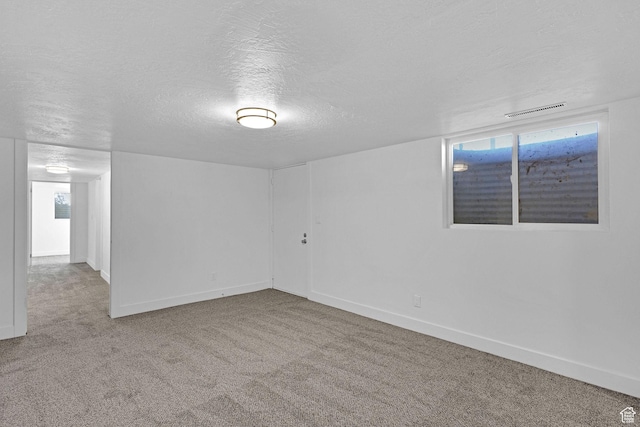 carpeted empty room featuring a textured ceiling