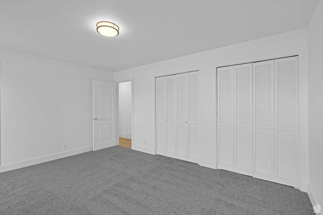 unfurnished bedroom with multiple closets, carpet floors, and a textured ceiling