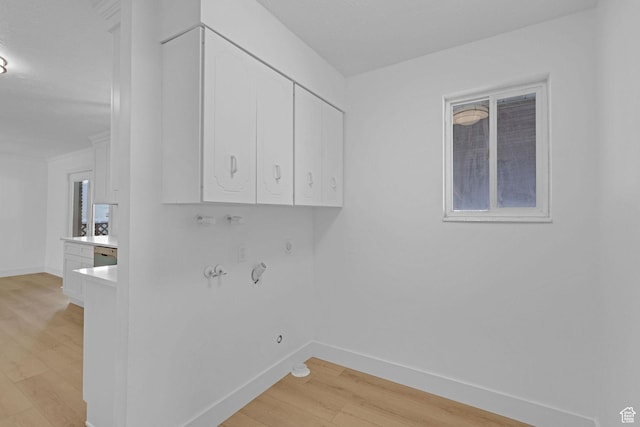 washroom featuring hookup for a gas dryer, cabinets, and light hardwood / wood-style flooring